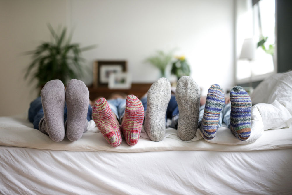 Artikkel om strømsparetips. Føtter med raggsokker over en sofakant.